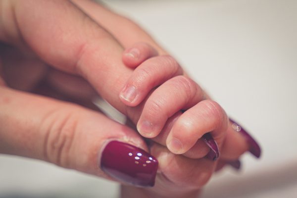 Säugling hält Mamas Hand